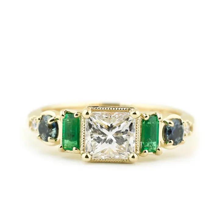 Custom engagement ring with large emerald and sapphire accent stones.